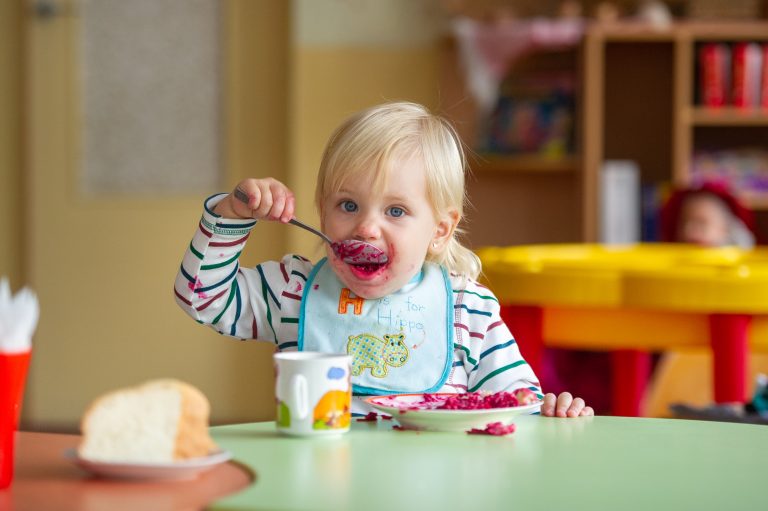 the child eats healthy food in kindergarten or at home and gets dirty.